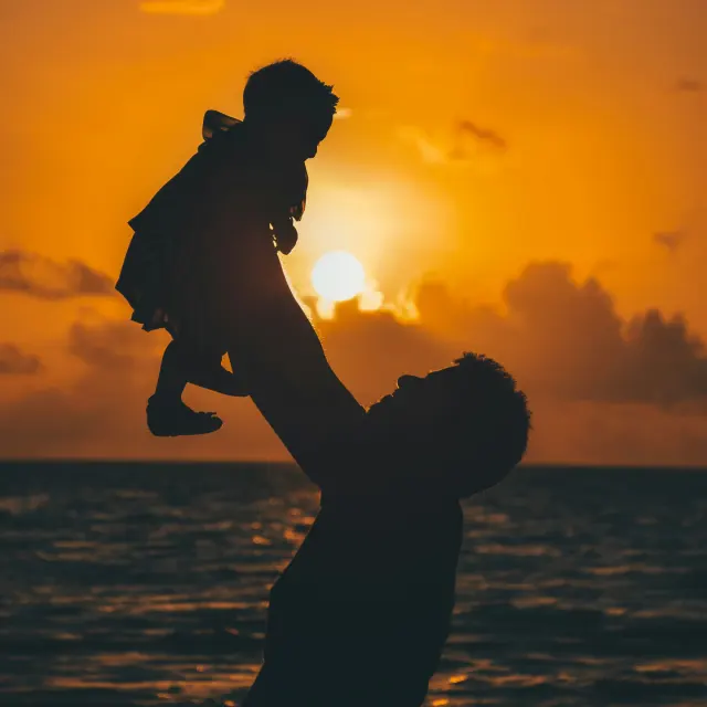 Pappa lyfter dotter på stranden